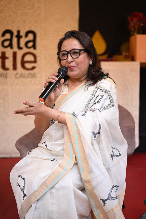 A_woman_showcasing_a_white_sari_with_a_mirror_motif_sitting_on_the_chair_giving_her_view